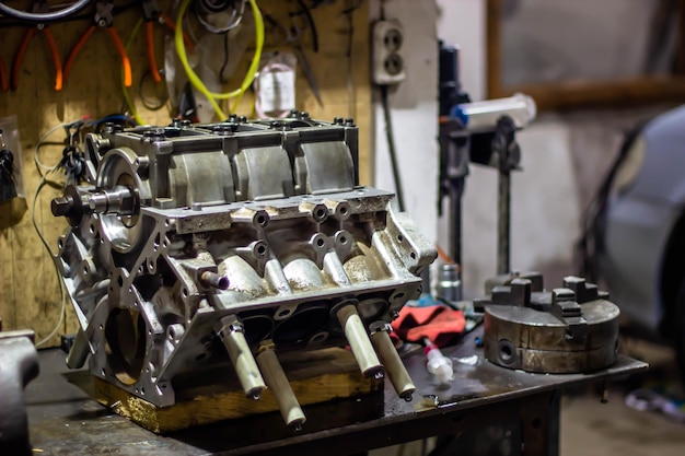 A close up of a car engine on a workbench with tools and tools.