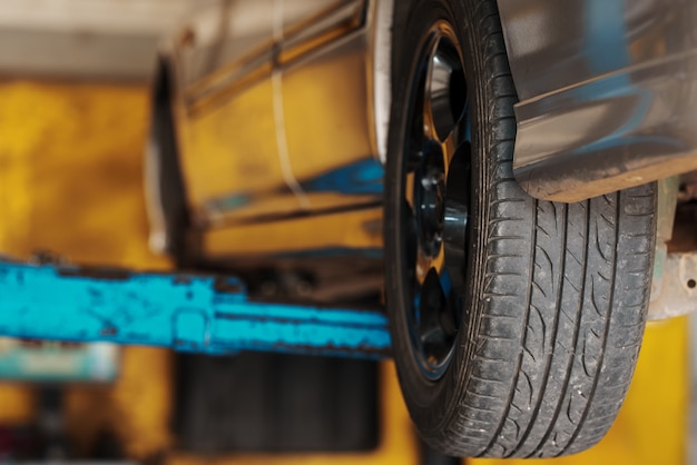 Close up Car mechanic replace tire on wheel in auto repair service workshop.