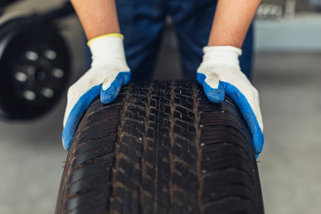 Photo close-up car service employee rolling wheel