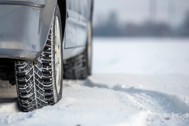 Close up of a car tire parked on snowy road on winter day. Transportation and safety concept.