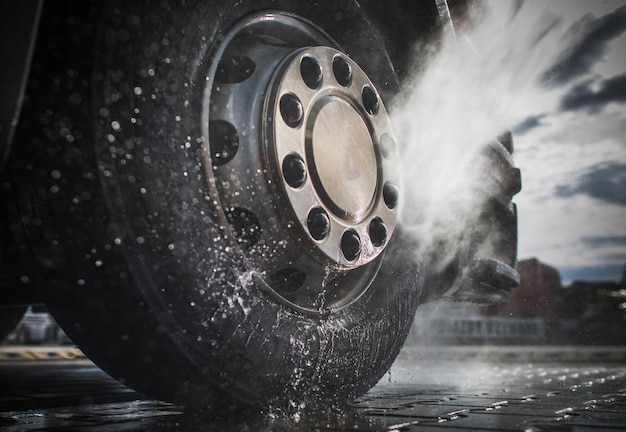 Photo close-up of car tire splashing water on road in city