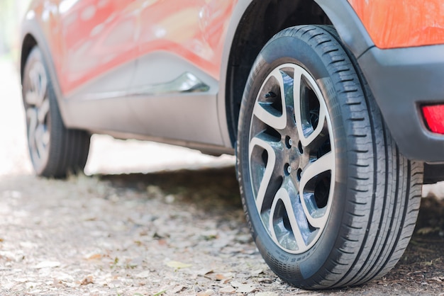 車のタイヤのクローズアップ。秋の紅葉で覆われた道路上の駐車中の車の背面図。