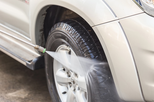 Chiuda sul lavaggio dell'automobile con il getto di acqua ad alta pressione