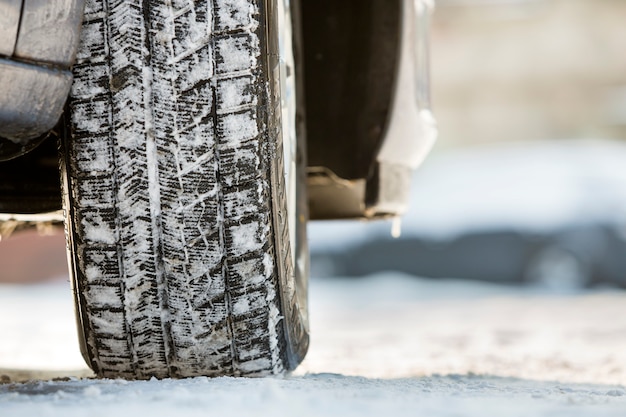 Close-up of car wheels rubber tire in deep snow. Transportation and safety concept.