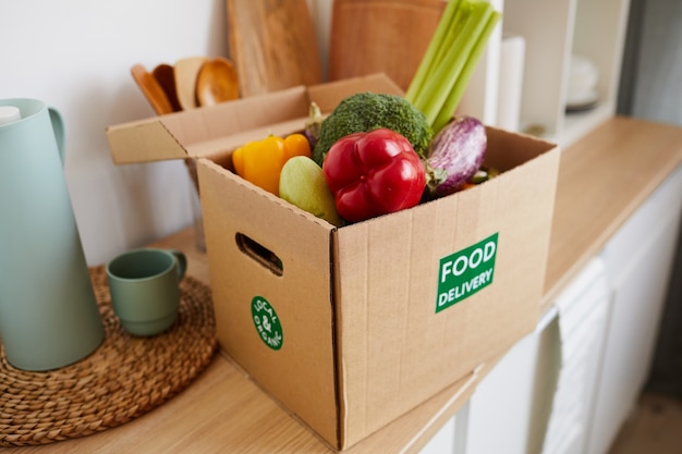 Close-up di una scatola di cartone con verdure fresche sul tavolo è la consegna del cibo