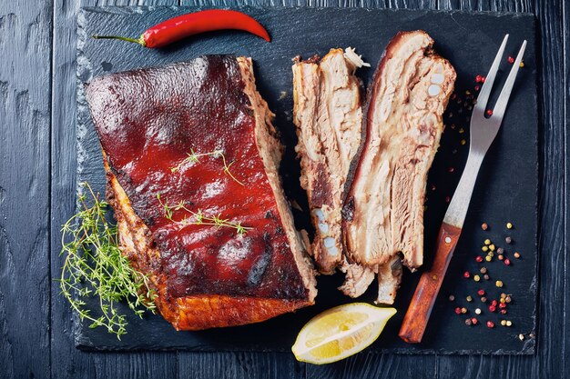 close-up of Caribbean roasted jerk pork belly with crispy charred skin on a black slate tray, view from above, flatlay,