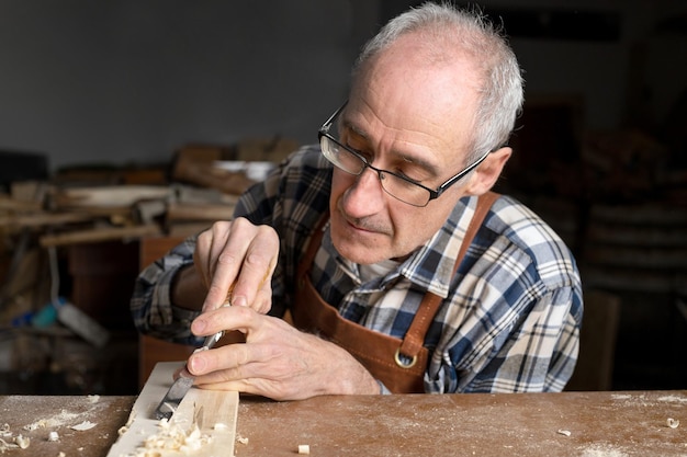 Primo piano di un falegname che intaglia il legno con lo scalpello