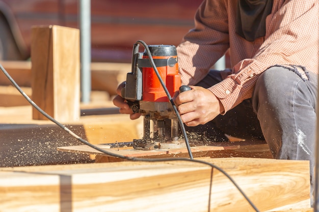 Закройте вверх планок руки плотника меля деревянных, работа на пиле отрезала древесину.