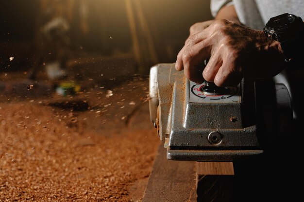 Photo close-up of a carpenter using a circular saw or a tool to cut wooden planks to make furniture