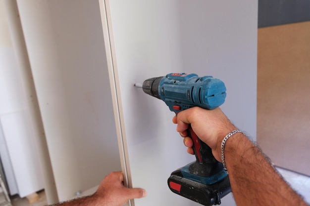 Photo close up. the carpenter works with wood on his workspace.carpentry uses a cordless drill to drill wo