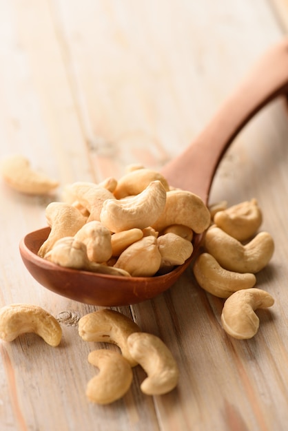 close up of cashew nuts in wood spoon on wood table