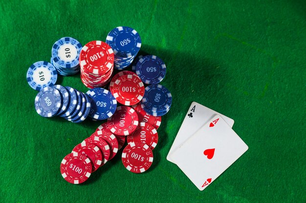 Close up of casino chips and two ACE cards on green table