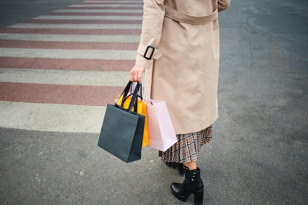 Close-up casual stijlvolle vrouw met boodschappentassen lopen op zebrapad