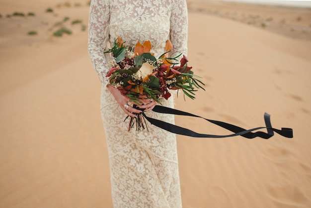 Foto chiuda su delle mani di una sposa caucasica che tengono un mazzo del bello fiore