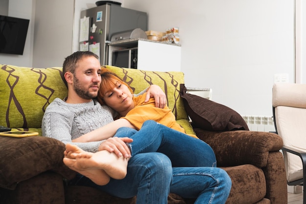 Photo close-up of a caucasian couple embracing on the couch at home watching television