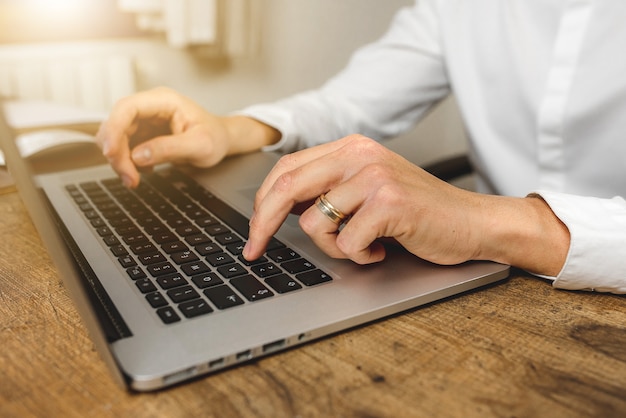 Close-up of caucasian man hand typing on laptop on office wooden desk. Typing mail. Shop online. Banking online. Typing on computer