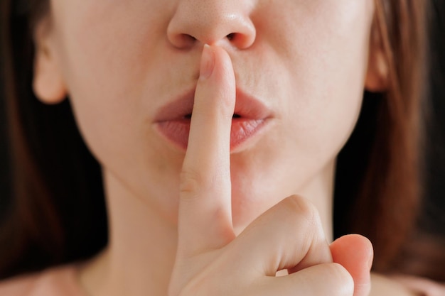 Close up of a caucasian woman portrait doing silence gesture with finger