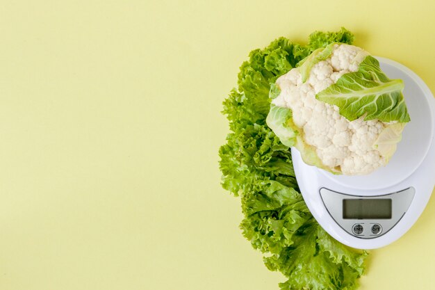 Close up on cauliflower and salad on scale