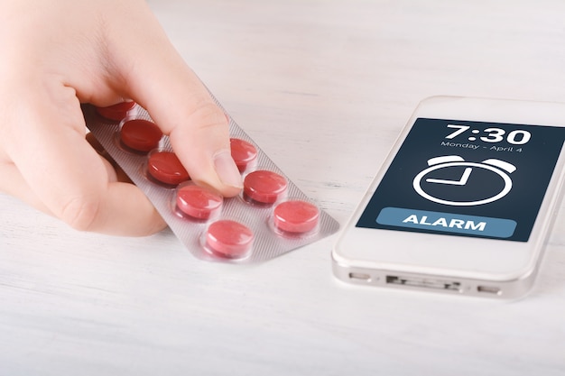 Close-up of cellphone alarm with pills