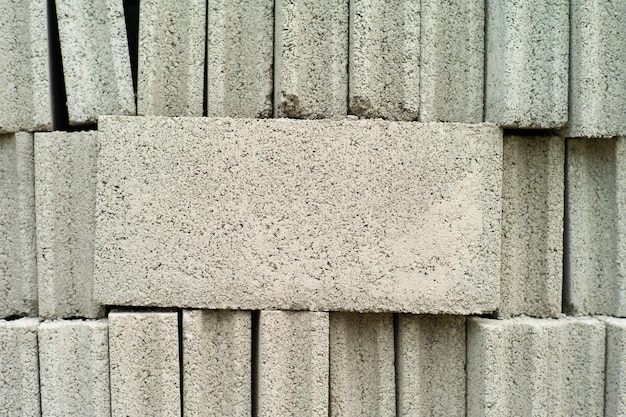 Photo close-up cement grey bricks out of the pile with blurred background at the construction site