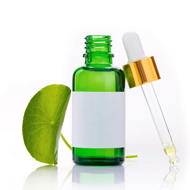 Close up centella asiatica extract in green bottles with centella asiatica leaves isolated on white background