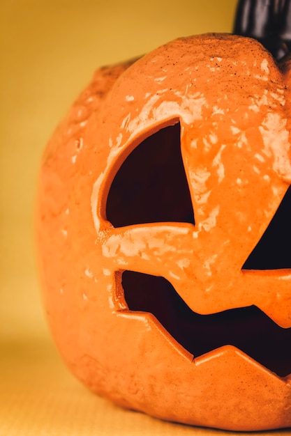 Foto primo piano di una zucca in ceramica con una faccia spettrale per la notte di halloween su sfondo giallo