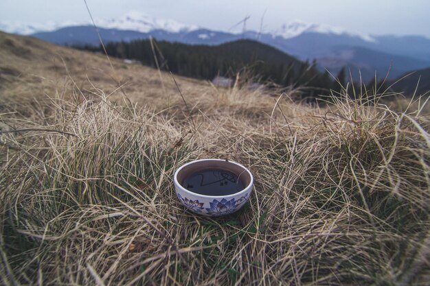 Close up ceramic tea mug standing in dried grass concept photo