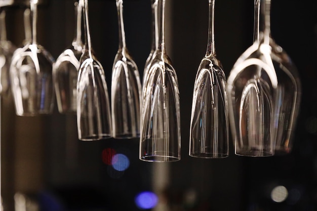 Photo close-up of champagne flutes hanging at bar during night