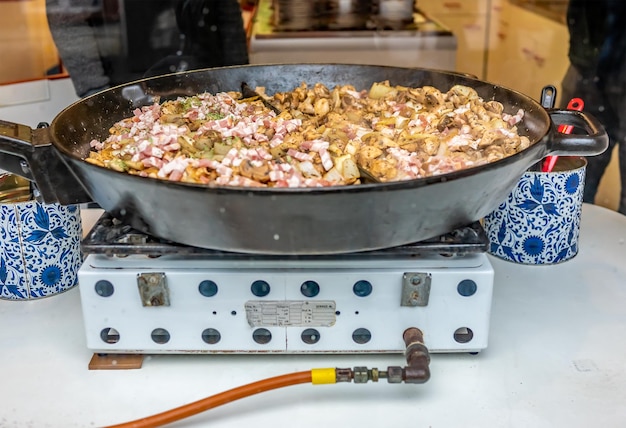 Photo close up of champignons and bacon being fried in front of a dirty glass shop window