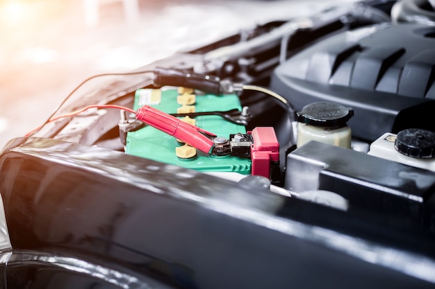 Photo close up charging car battery with electricity through jumper cables