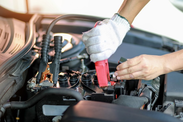 Photo close up charging car battery with electricity trough jumper cables.