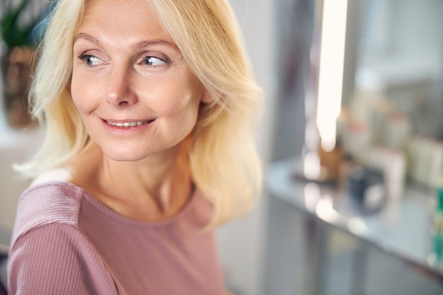 Close up of charming female person keeping smile on her face while having idea for the evening