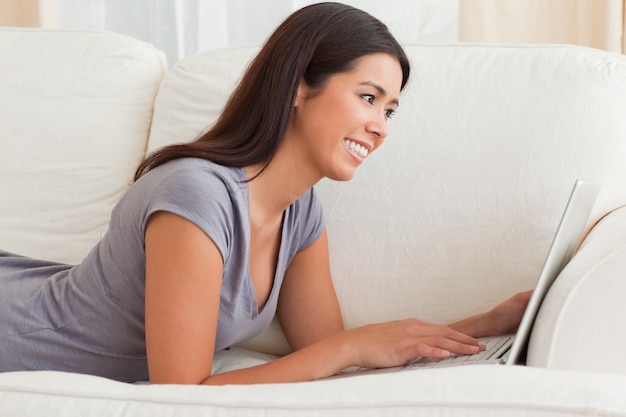 close up of a charming woman lying on sofa with notebook