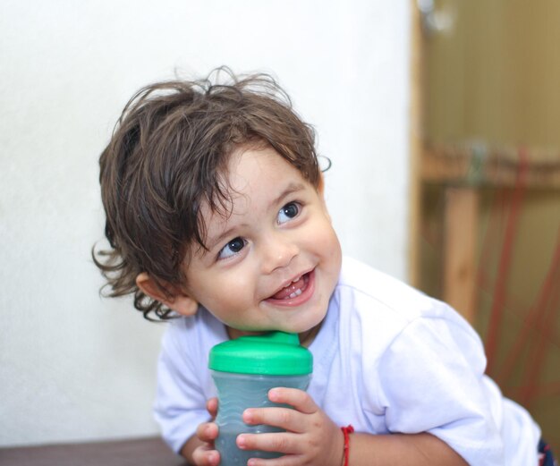 Close-up of cheerful baby boy having drink at home