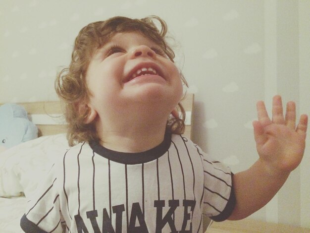 Close-up of cheerful boy looking up at home