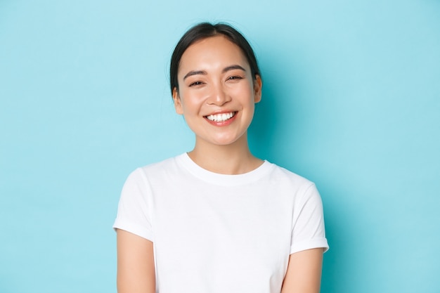 Close-up of cheerful carefree asian girl in white t-shirt smiling broadly.