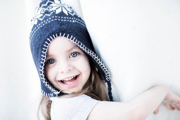 Photo close-up of cheerful girl wearing knit hat by curtain
