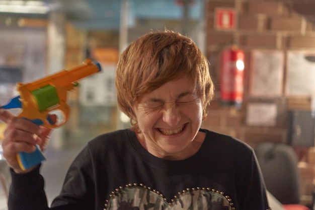 Photo close-up of cheerful woman shooting herself with toy handgun