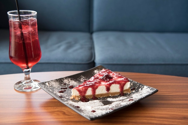 Foto close-up di cheesecake in piatto con bevanda alla fragola sul tavolo