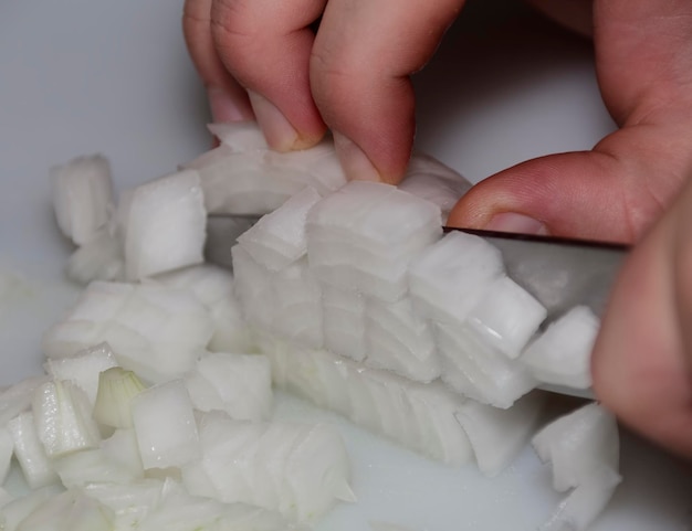 Photo close-up of a chef hand cutting onions