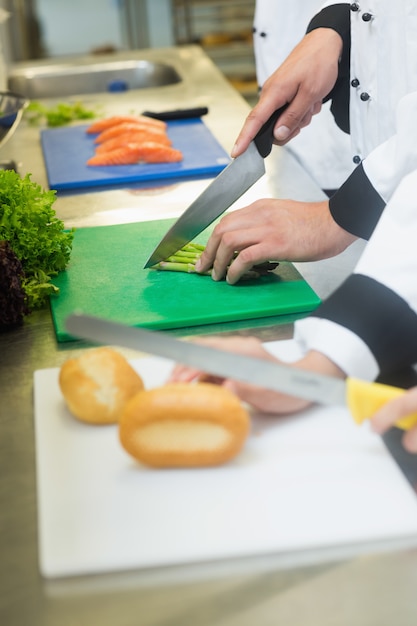 Close up of chefs slicing bread rolls and asparagus