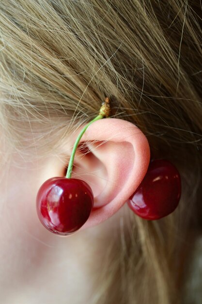 Close-up of cherries on woman ear