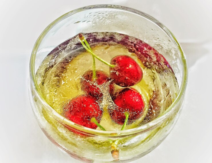 Photo close-up of cherry drink in glass on white background