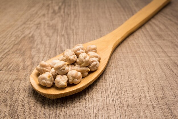 Close-up of chick-peas in spoon on wooden table