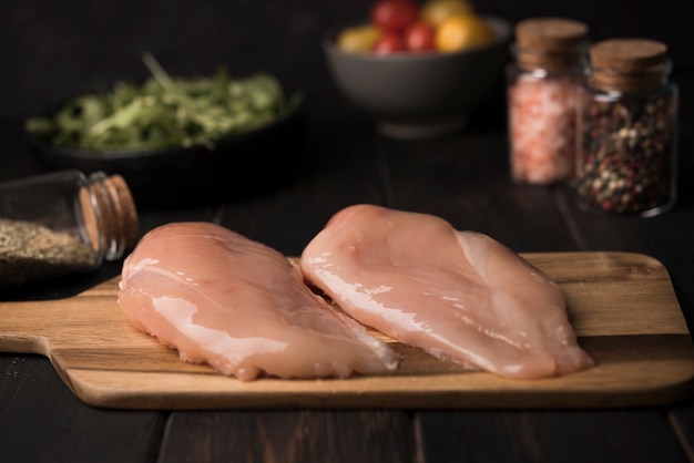 Foto petto di pollo del primo piano sul bordo di legno con gli ingredienti