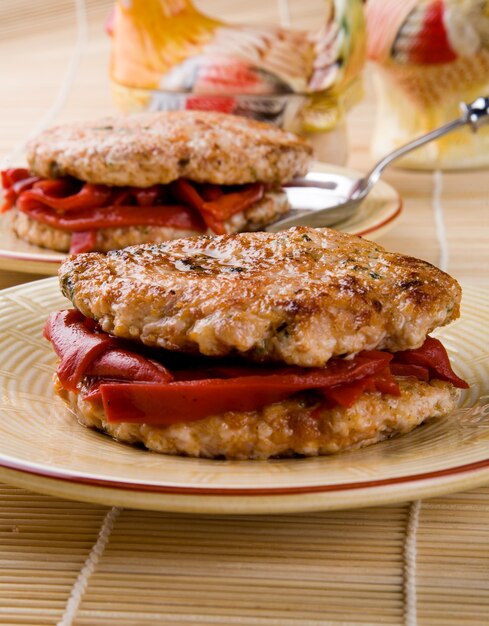 Close-up chicken burgers with red peppers plated with blurred background