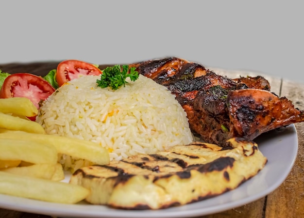 Close up of chicken dish with gallo pinto and pico de gallo on wooden table Top view of roasted chicken dish with rice t french fries served on wooden background Concept of typical Nicaraguan food