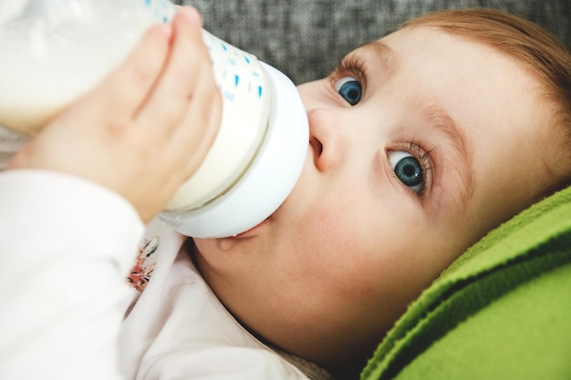 Foto close-up di un bambino che beve latte dalla bottiglia