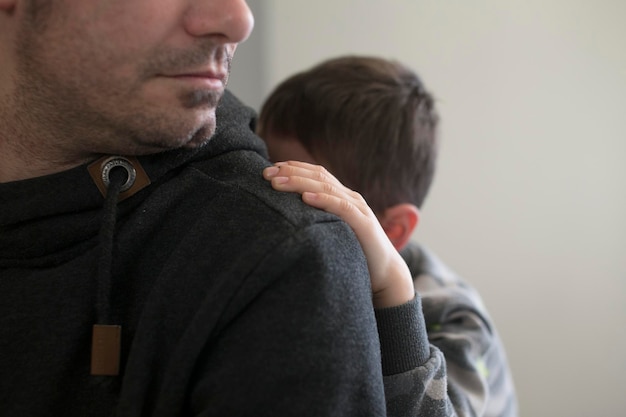 Foto prossimo piano mano di bambino su spalla di uomo contro il muro