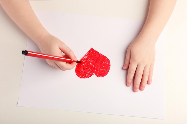 Close-up of child hands drawing a red heart